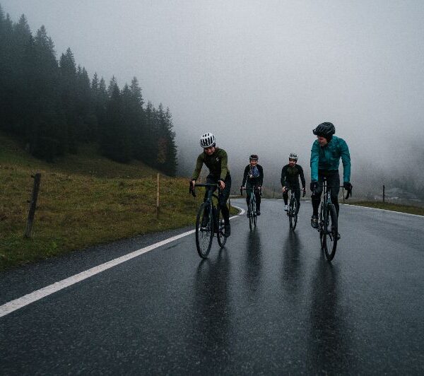 Ciclistas de jaqueta pedalando em uma rua molhada no inverno