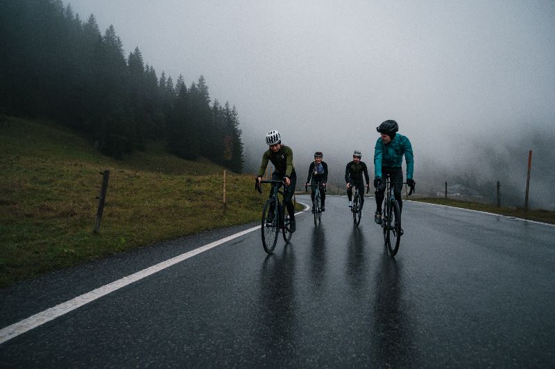 Ciclistas de jaqueta pedalando em uma rua molhada no inverno