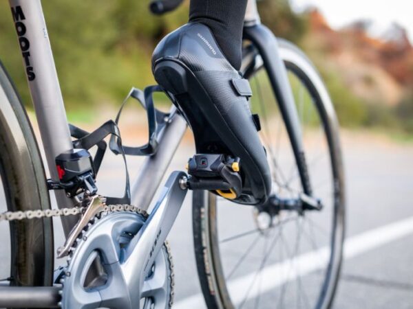 Imagem de close-up de taco de pedal de bicicleta desgastado ao lado de um novo, em um ciclista numa rua