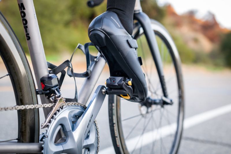 Imagem de close-up de taco de pedal de bicicleta desgastado ao lado de um novo, em um ciclista numa rua